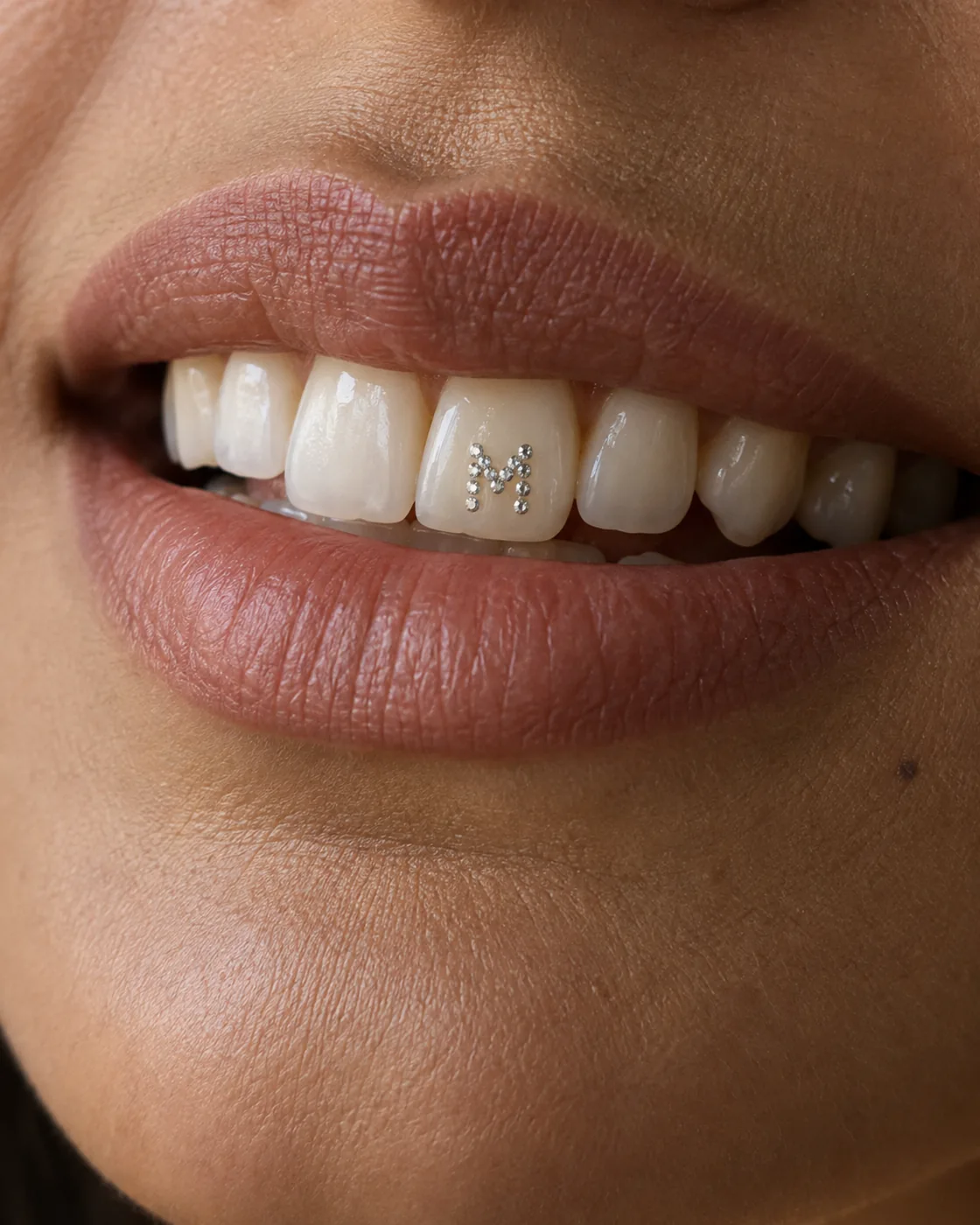The letter M composed of tiny clear crystals.